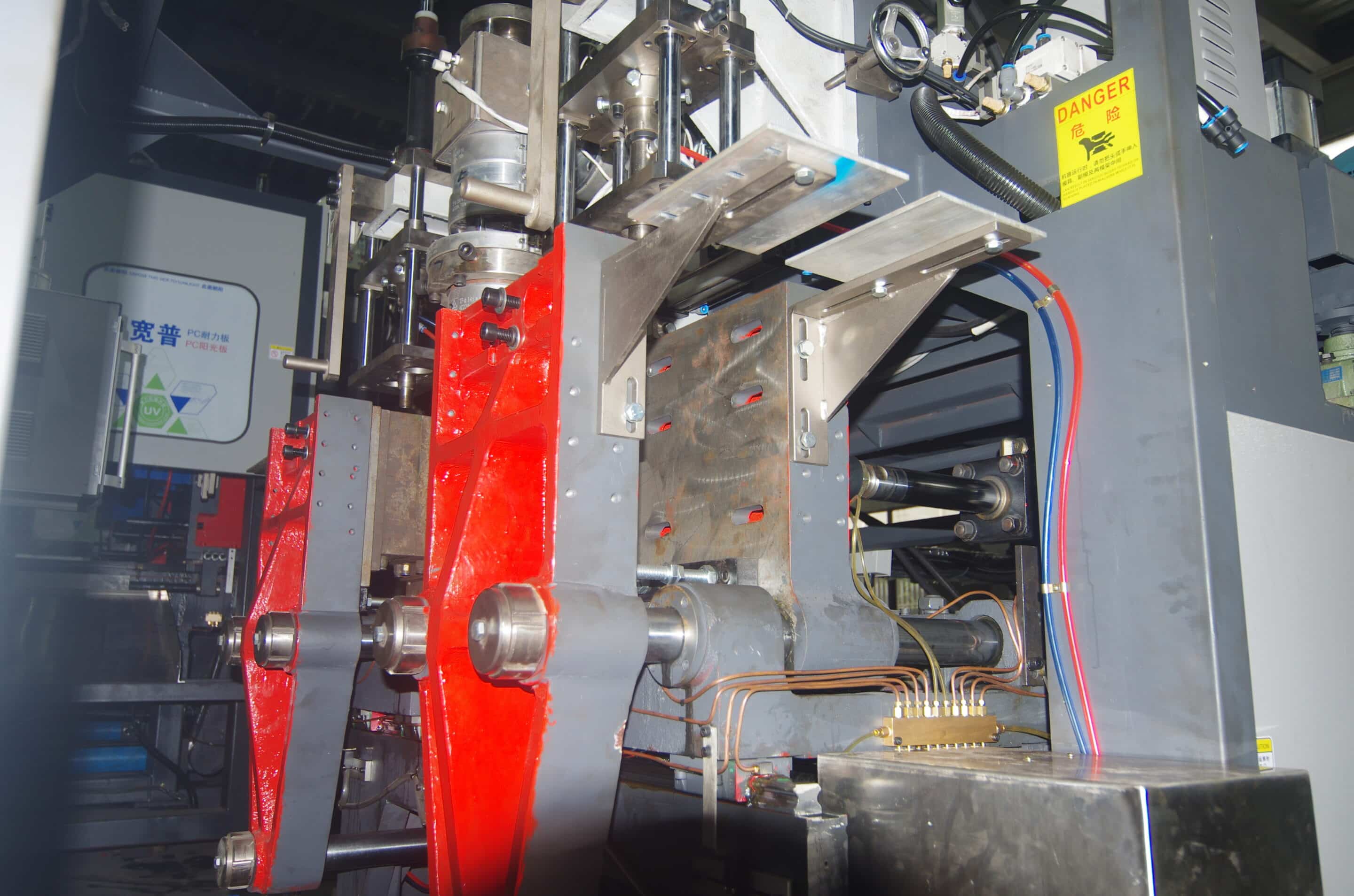 Side view of automatic take-out gripper and chute beside mold carriers under the die head