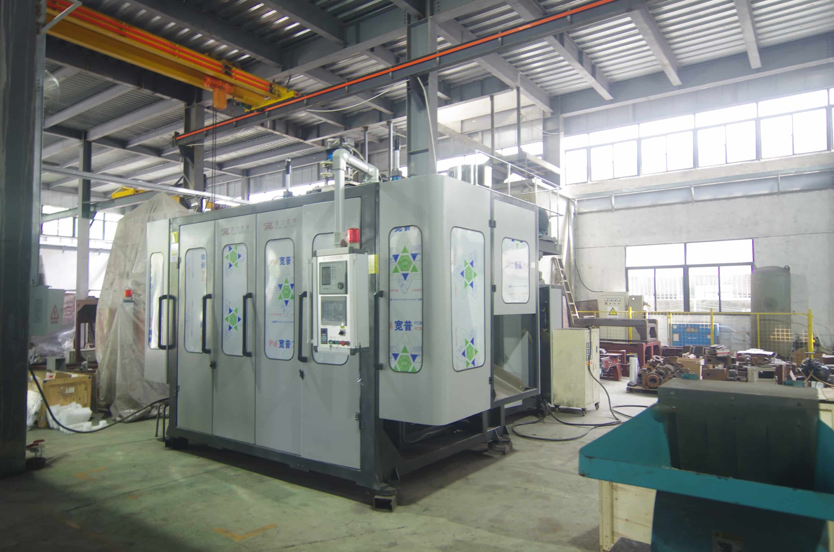 Enclosed extrusion blow molding machine cell with safety doors and side-mounted HMI in workshop