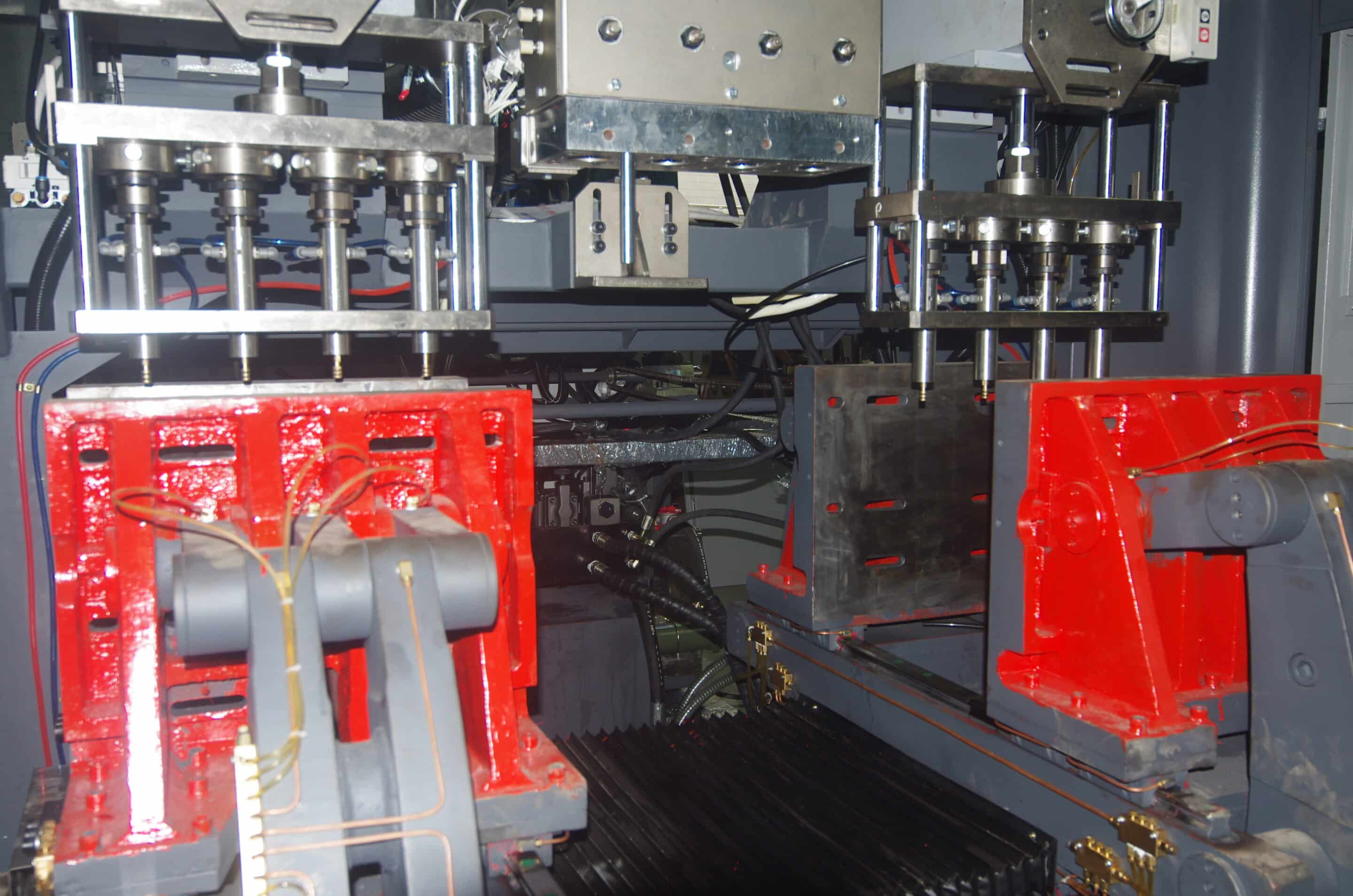 Dual clamping units with upper cutter heads and central die head inside blow molding machine