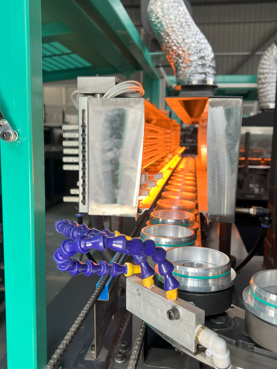 IR heating tunnel with puck conveyor in PET stretch blow molding machine.