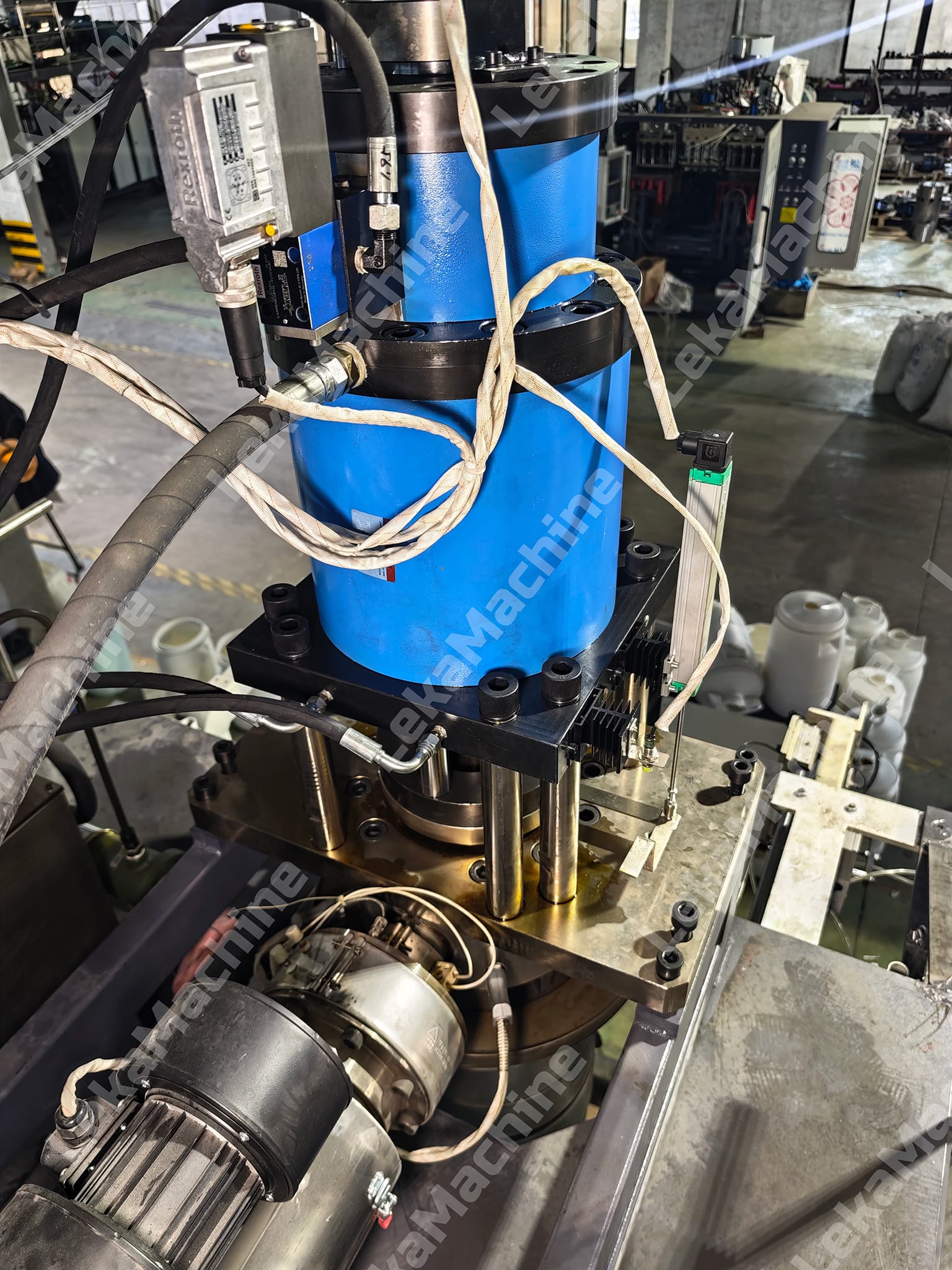 Extrusion blow molding machine head with blue hydraulic cylinder and hoses