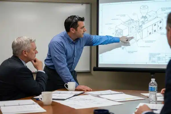 Un ingénieur examine les spécifications techniques d'une machine de moulage par soufflage avec le PDG dans la salle de réunion (ID#1)