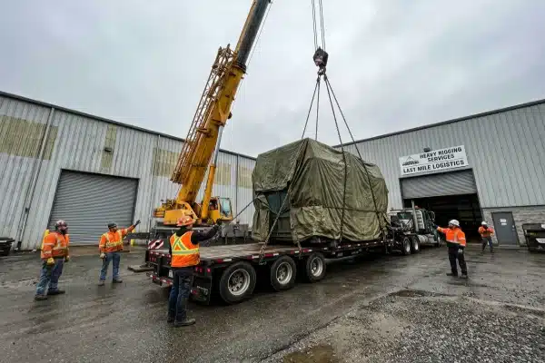 Crane lifting heavy blow molding machine during industrial logistics and rigging setup (ID#2)